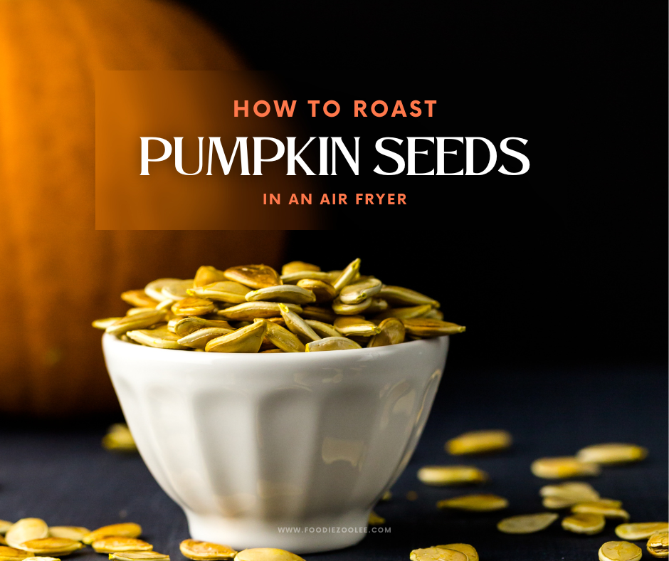 A vibrant image of a small white bowl filled with golden, roasted pumpkin seeds, with a few seeds scattered around it. The background is dark, with the soft, blurred image of a pumpkin visible on the left side. The text "How to Roast Pumpkin Seeds in an Air Fryer" is displayed prominently above the bowl in bold, stylish fonts, with "How to Roast" in orange and "Pumpkin Seeds" in white. The website URL "www.foodiezoolee.com" is subtly positioned below the bowl. The overall composition conveys a clean, inviting feel with an autumn theme.